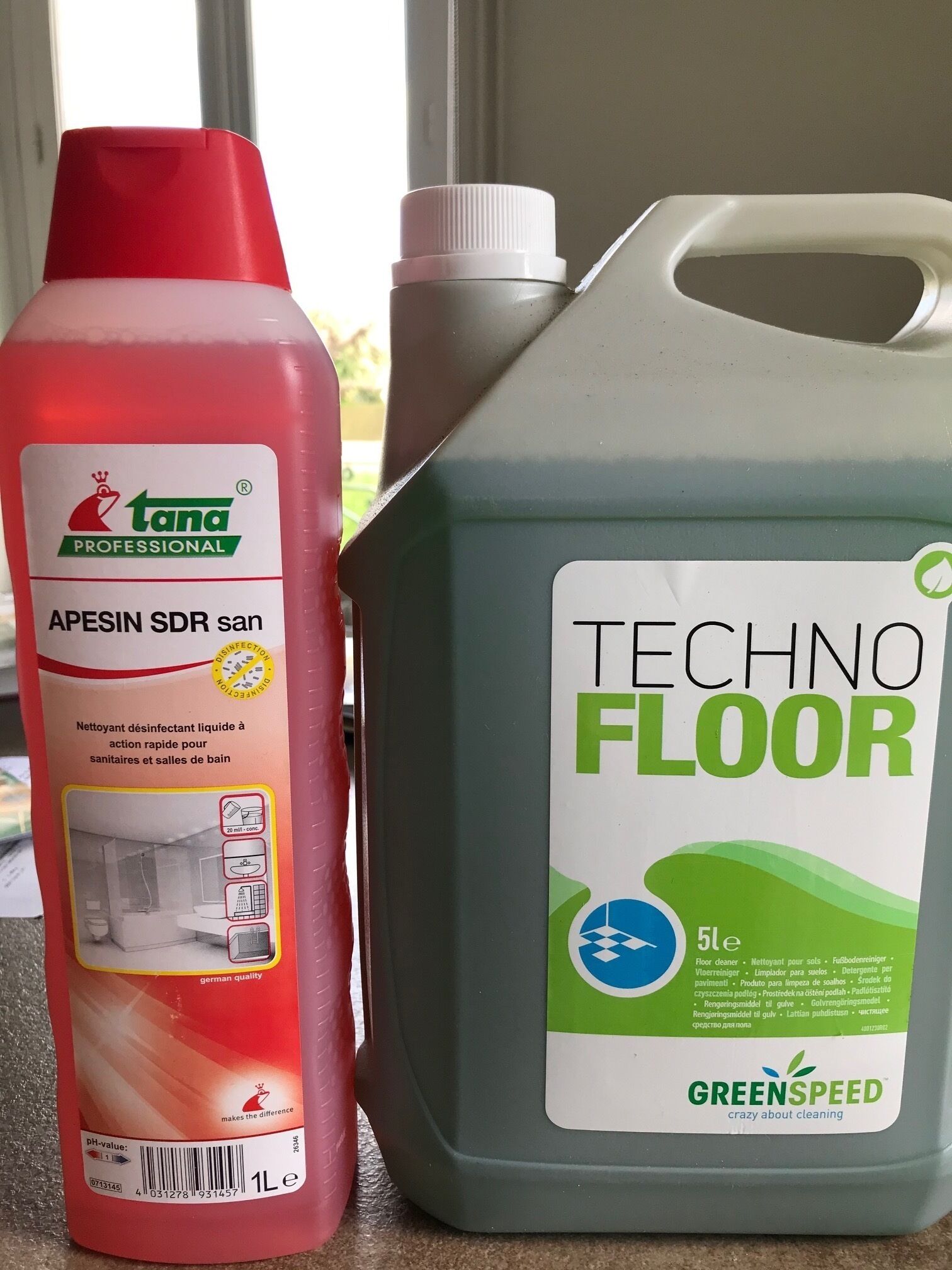 Two cleaning products, one red and one grey, on a countertop.