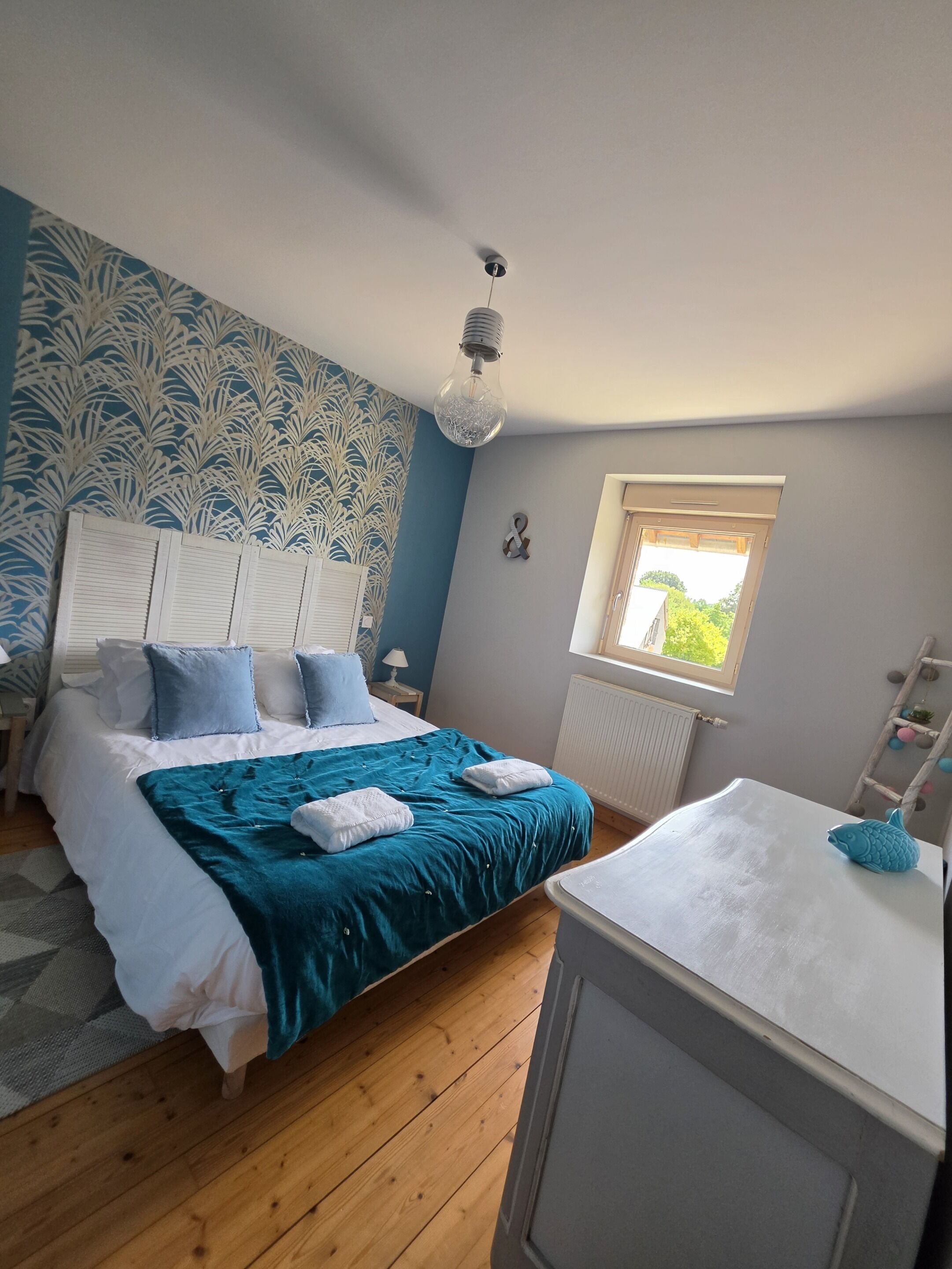 Une chambre à coucher avec un lit, des tables de chevet, une fenêtre et un radiateur.