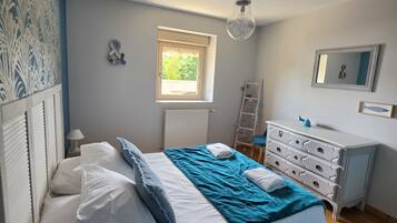 Ein Schlafzimmer mit Bett, Kommode, Fenster und Heizkörper.