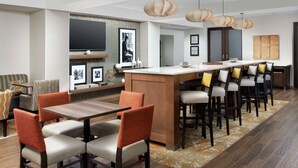 A modern hotel lobby with a bar area, seating arrangements, and a large flat-screen TV mounted on the wall. - Hampton Inn Denver Tech Center South CO (Englewood)