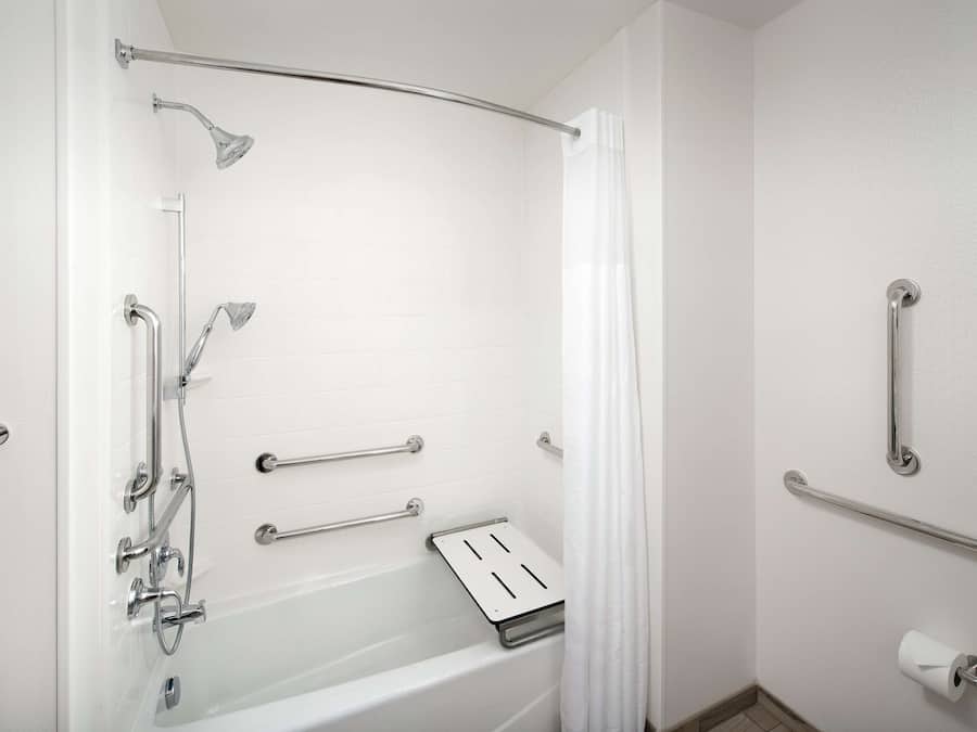 A modern bathroom with a walk-in shower, grab bars, and a toilet paper holder.