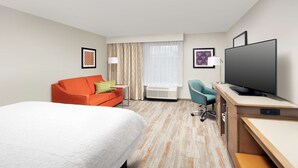 A hotel room with a bed, a desk, a television, a chair, and a window with curtains. - Hampton Inn Denver Tech Center South CO (Englewood)