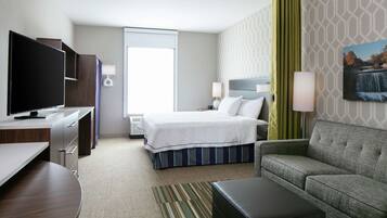 A hotel room with a bed, a sofa, a TV, a desk, and a window.
