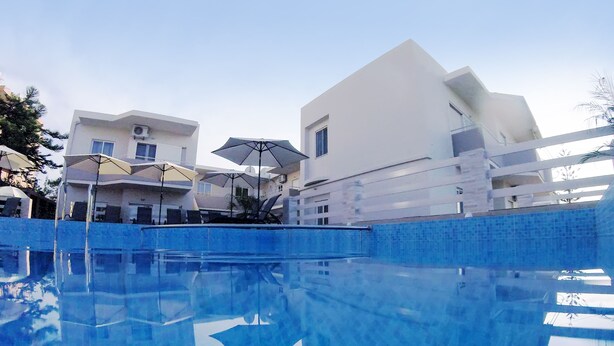 Une piscine à l’eau d’un bleu cristallin, entourée de bâtiments modernes aux façades blanches et dotés de balcons.