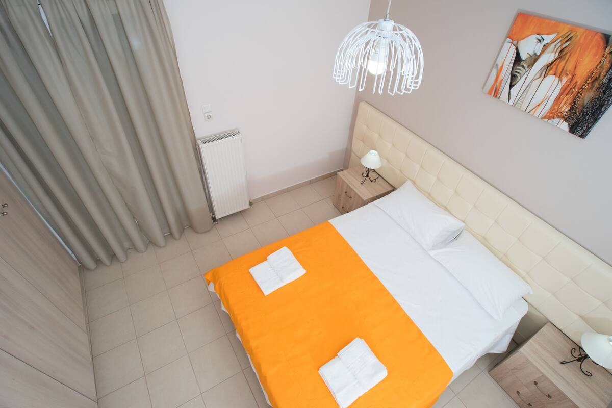 Une chambre d’hôtel avec un lit, une table de chevet, une lampe, un radiateur et un tableau au mur.