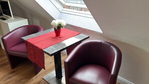 Een klein eetgedeelte met een tafel, stoelen en een vaas bloemen.