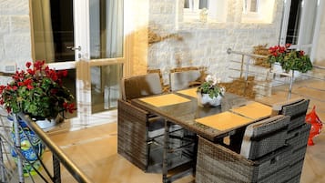 A dining area with wicker furniture, a glass table, and potted plants.