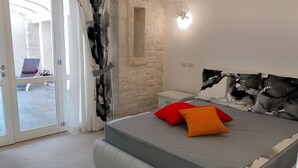 A bedroom with a bed, a nightstand, a window, and a door.