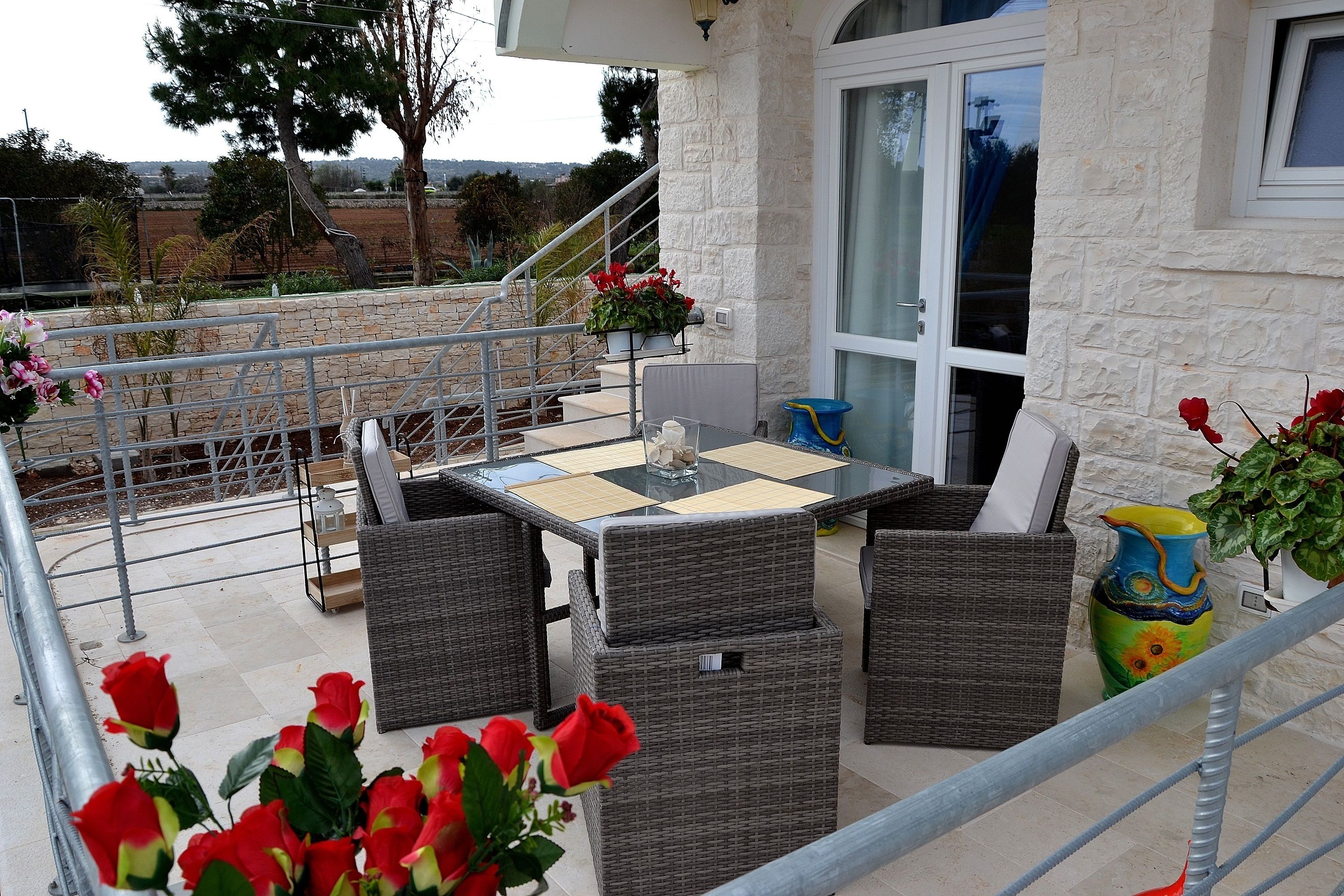 Une terrasse extérieure aménagée avec des meubles en osier, une table et des plantes en pot.