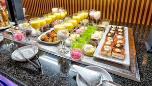 Un bufé con diversos postres, bebidas y una botella de licor.