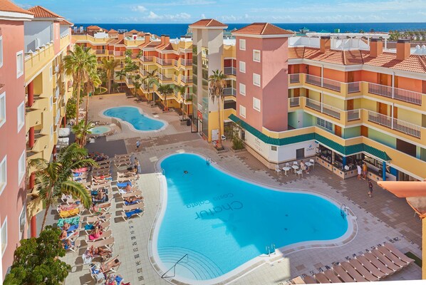 Un resort con varias piscinas, zona de playa y vista al océano.