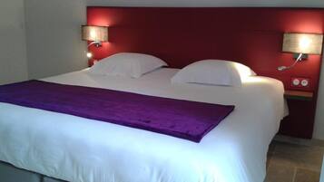 A hotel room with a large bed, two bedside lamps, and a red headboard.