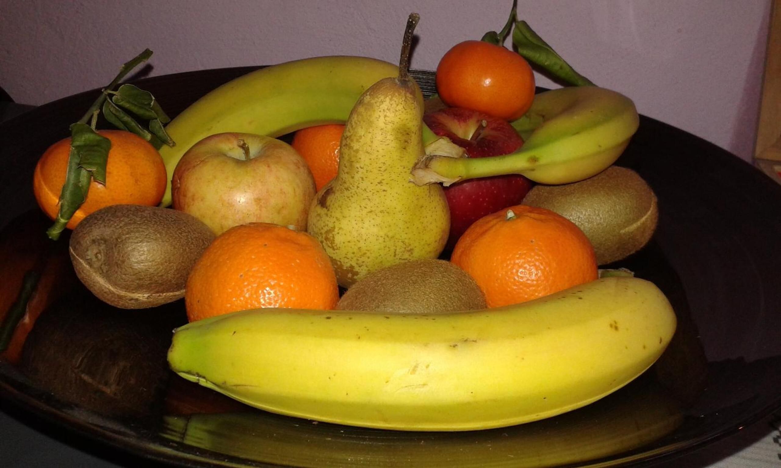 Un tazón con frutas variadas, como plátanos, manzanas, naranjas y peras.