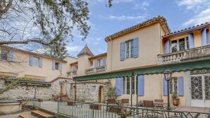 A courtyard with outdoor seating, stone walls, and a building with blue shutters. - Logis Hôtel Le Domaine de la Régalière (Anduze)