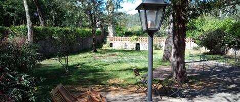 A park with a paved path, wooden benches, a lamp post, and a stone wall.
