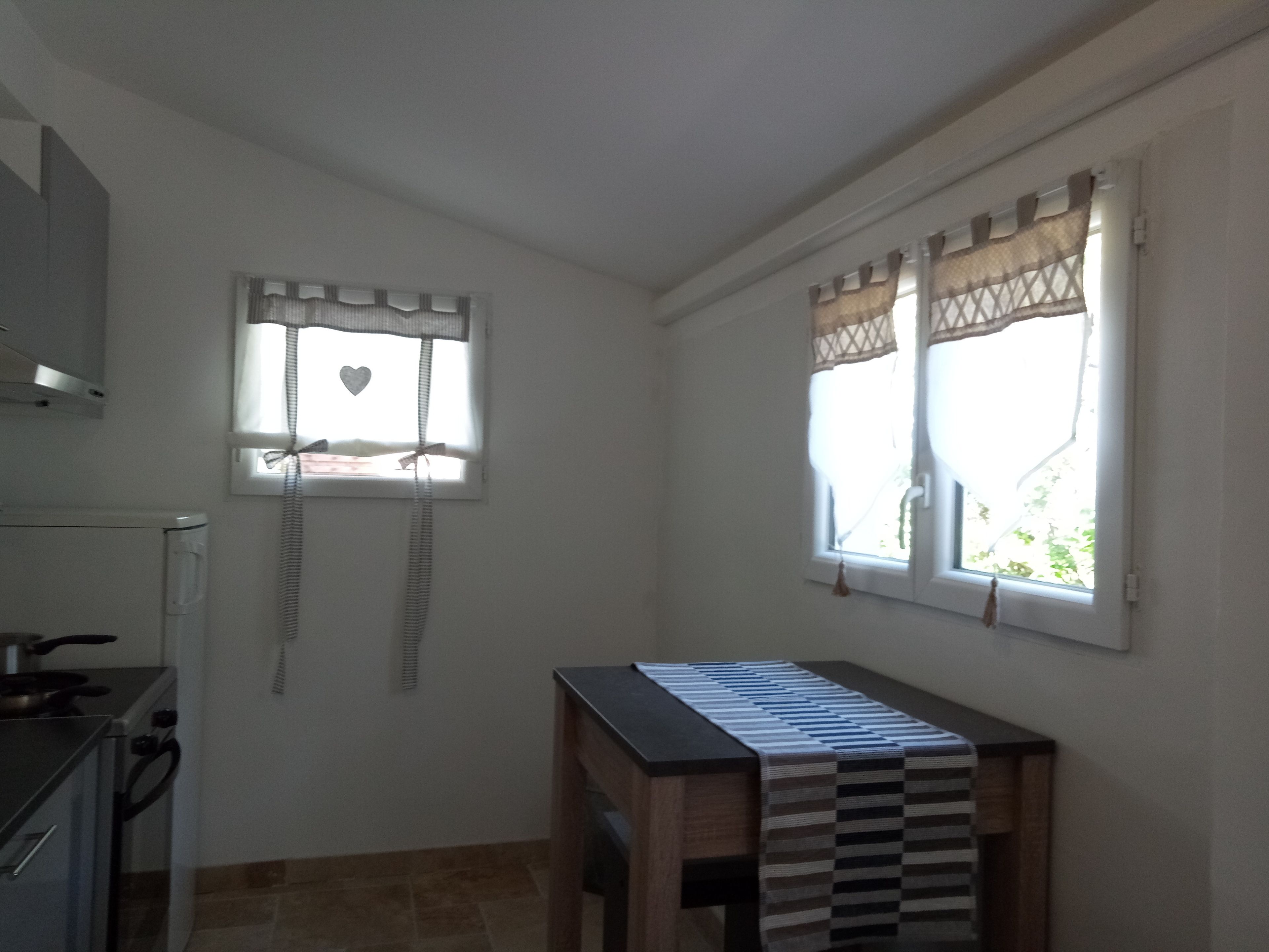 A kitchen with a stove, a sink, and a window with curtains.