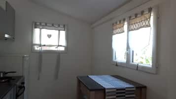 A kitchen with a stove, a sink, and a window with curtains.
