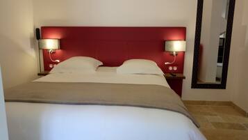 Ein Hotelzimmer mit einem großen Bett, zwei Nachttischen mit Lampen, einem roten Kopfteil und einem Spiegel an der Wand.