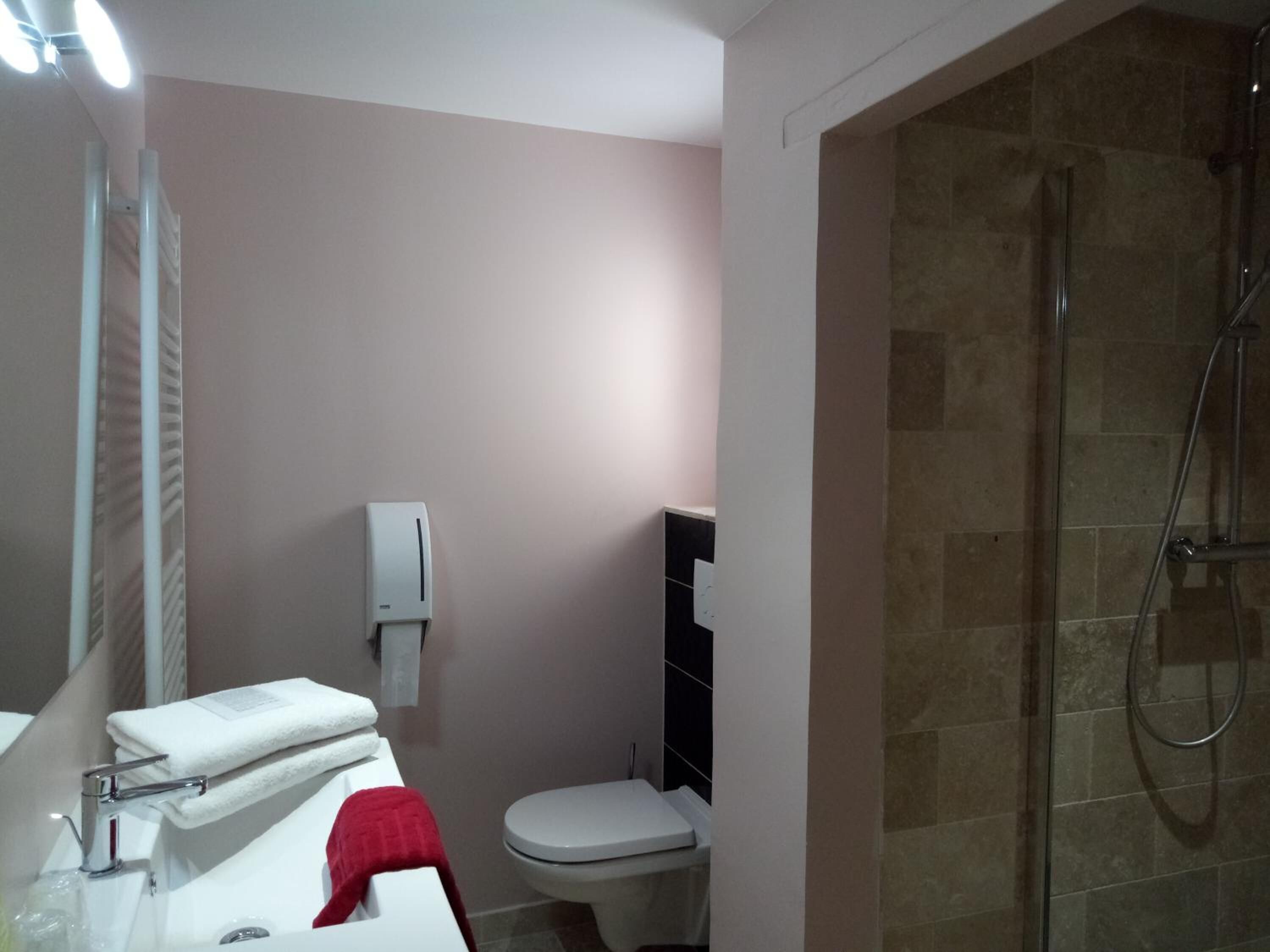 Ein Badezimmer mit Dusche, Toilette, Waschbecken und Handtuchhalter.