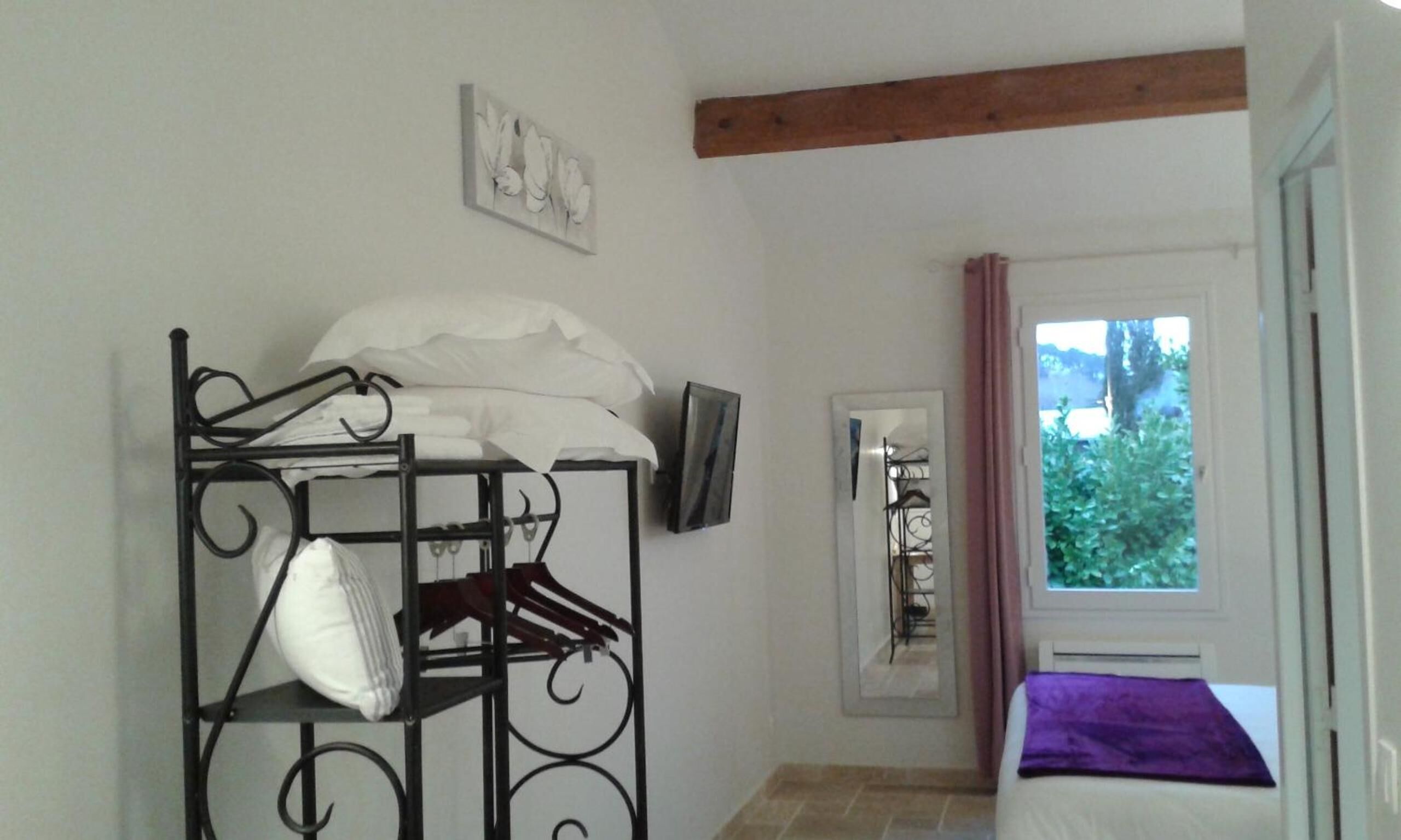 Una habitación con literas, un televisor montado en la pared, una ventana con cortinas y una puerta que da a otra habitación.