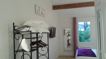 Una habitación con literas, un televisor montado en la pared, una ventana con cortinas y una puerta que da a otra habitación.
