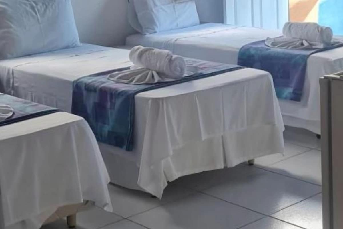 Una habitación de hotel con dos camas individuales, cada una con una colcha blanca y una toalla azul.
