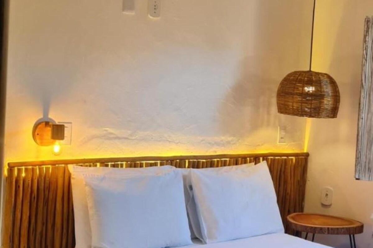 Un dormitorio con cama, mesita de noche, lámpara y apliques en la pared.