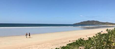 Una playa con cielo despejado y una montaña a lo lejos.