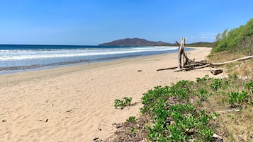 Di pantai, pasir putih, handuk pantai, dan berselancar