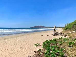 A beach with a clear sky, sandy shore, and a distant mountain. - Hotel El Manglar & Cantarana (Cabo Velas)