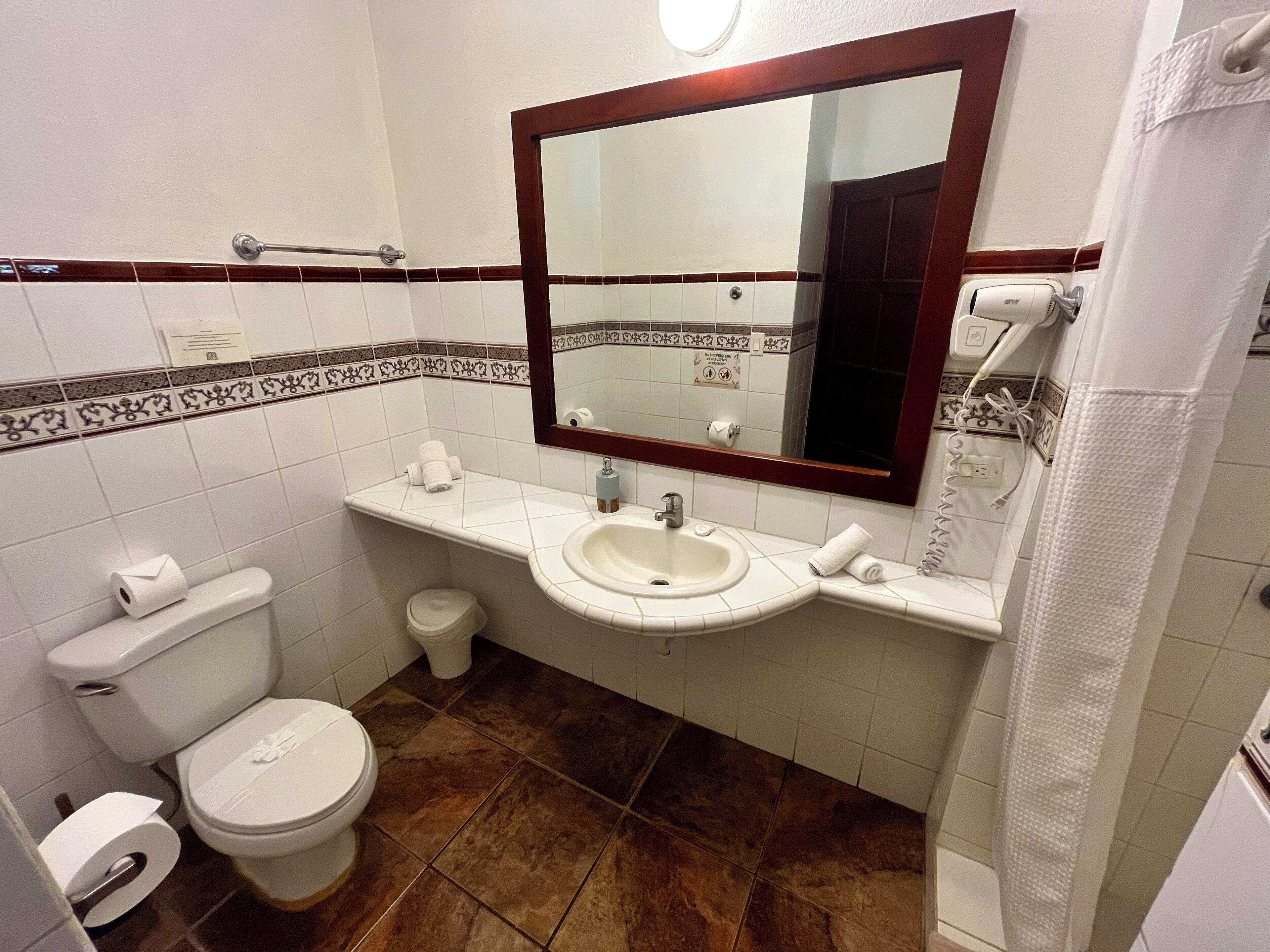 A bathroom with a toilet, sink, and mirror.