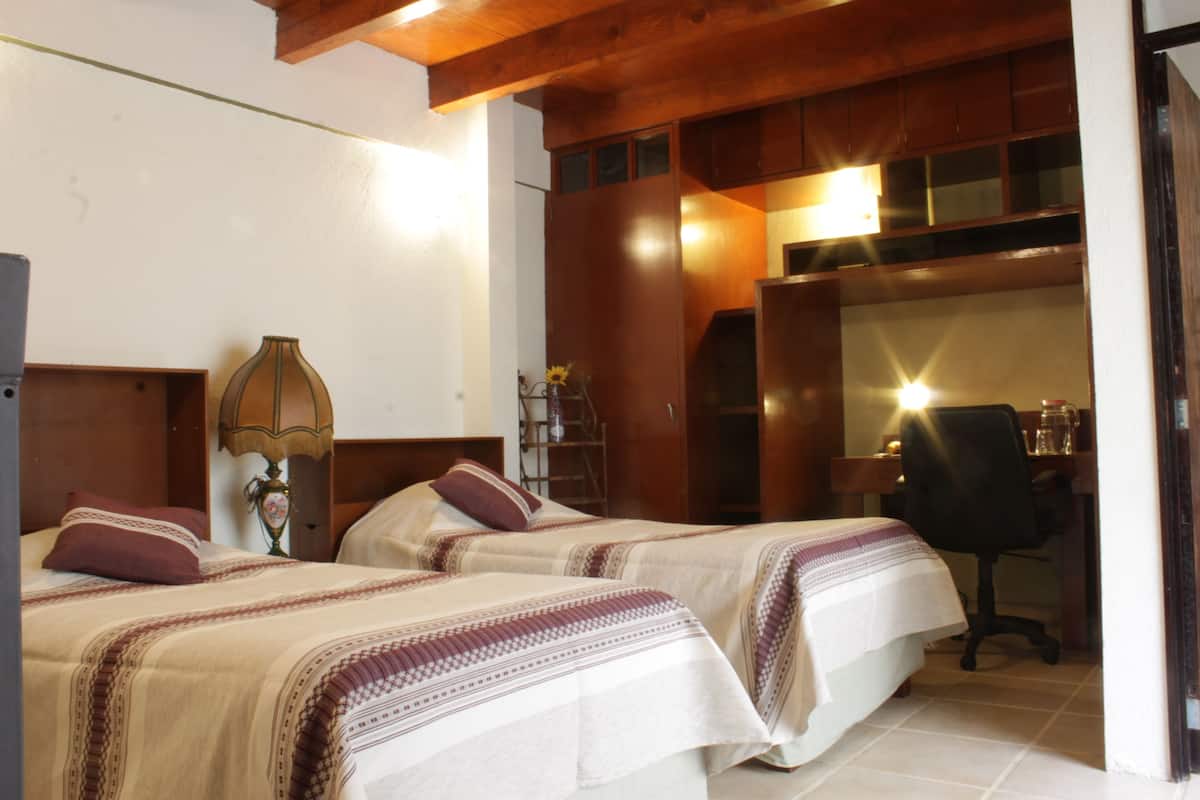 Une chambre d’hôtel avec deux lits, un bureau et une chaise.