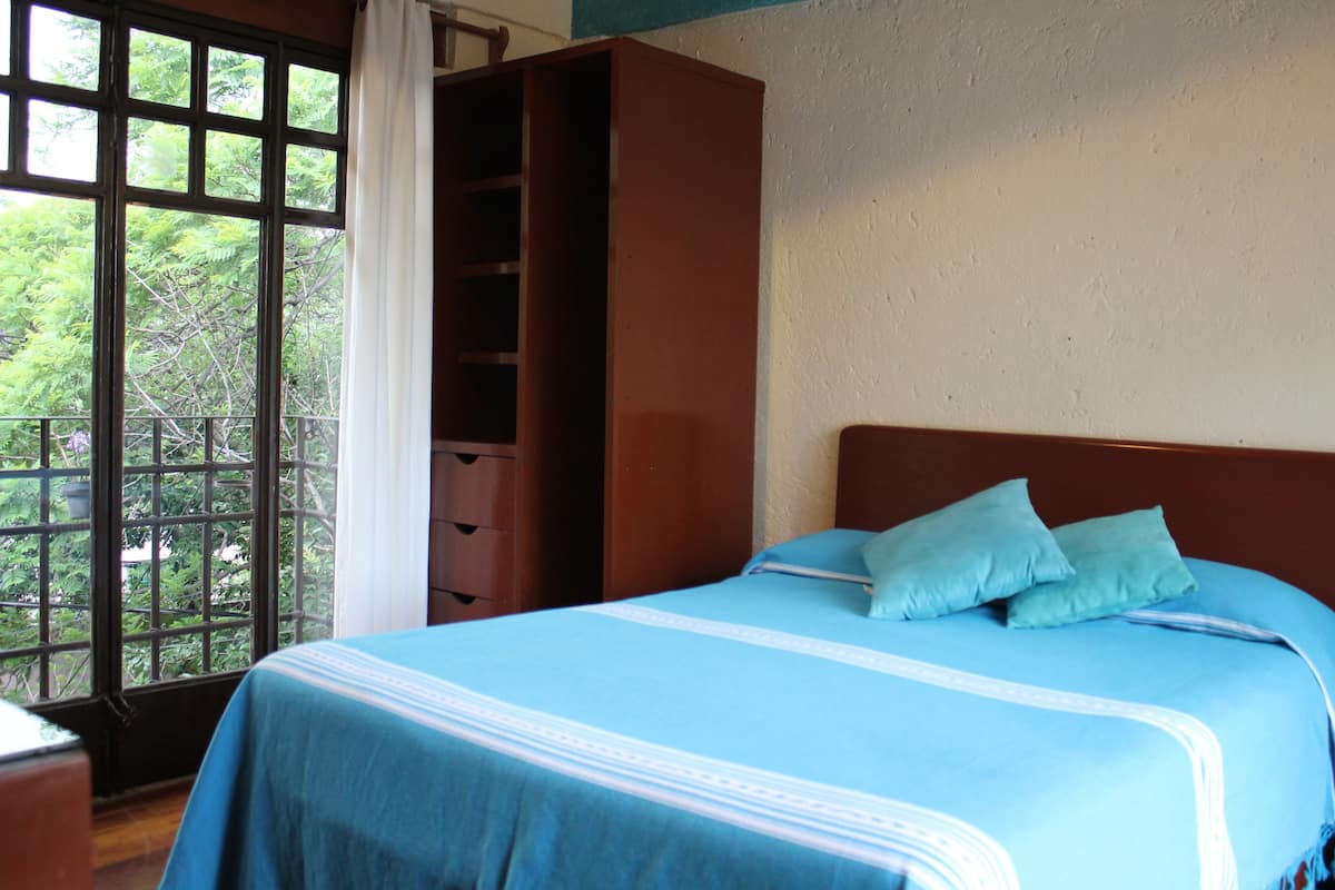 Une chambre à coucher avec un lit, une armoire et une fenêtre donnant sur des arbres.