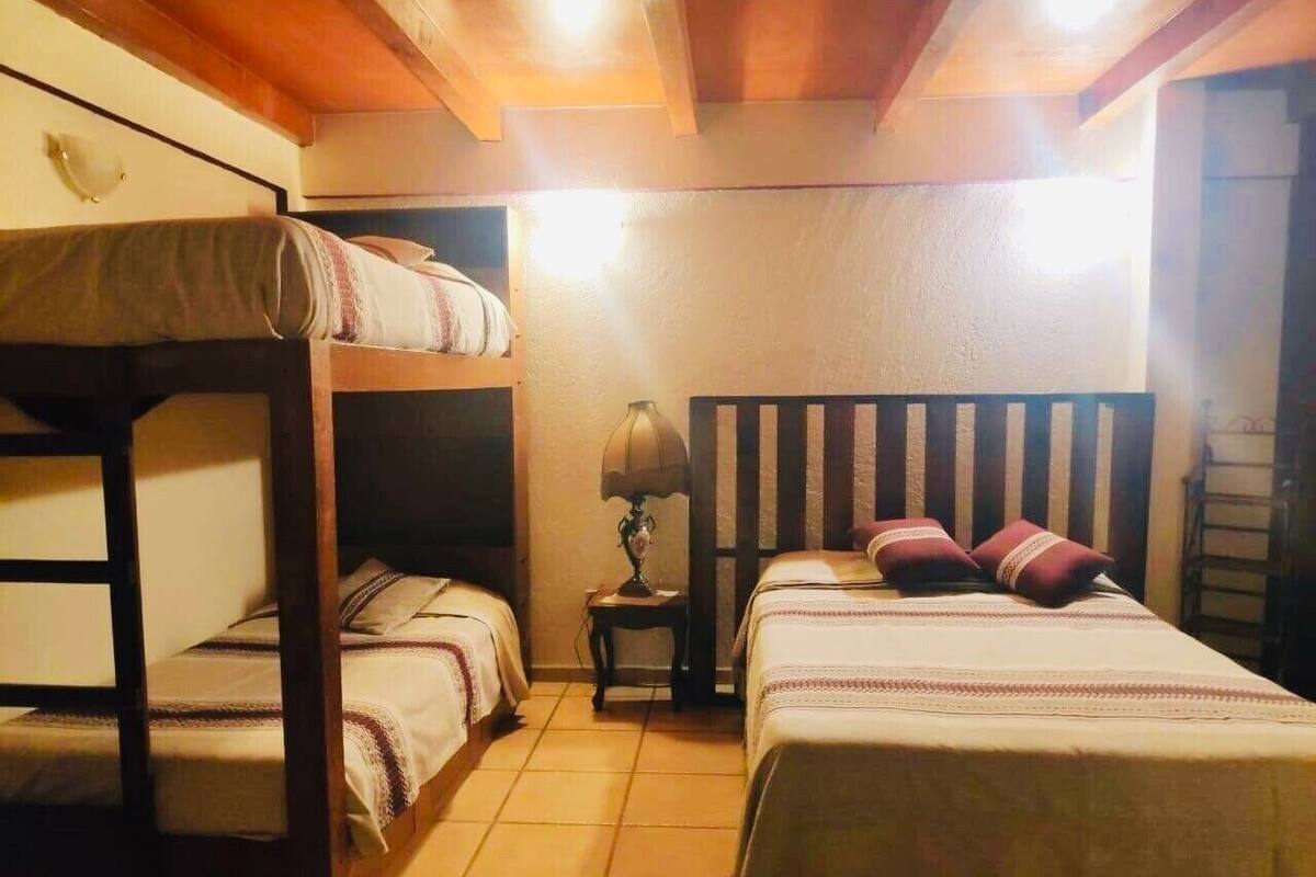 Une chambre de dortoir avec des lits superposés, une lampe de chevet et une tête de lit en bois.
