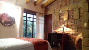Een slaapkamer met een bed, een bureau en een stenen openhaard.