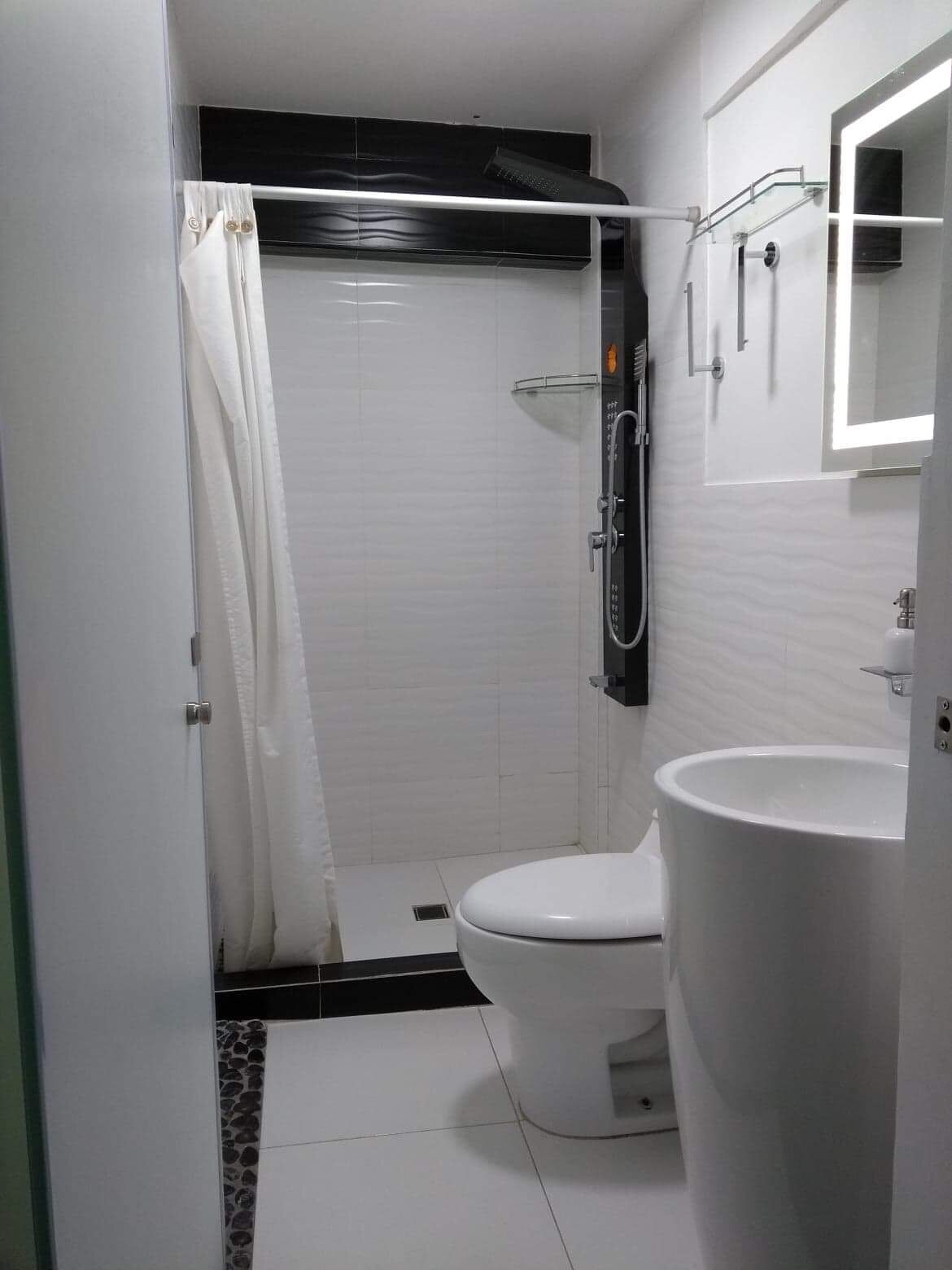 A modern bathroom with a shower, toilet, and sink.