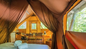 A cozy tent with a bed, a small table, and chairs. - Huttopia White Mountains (Conway)