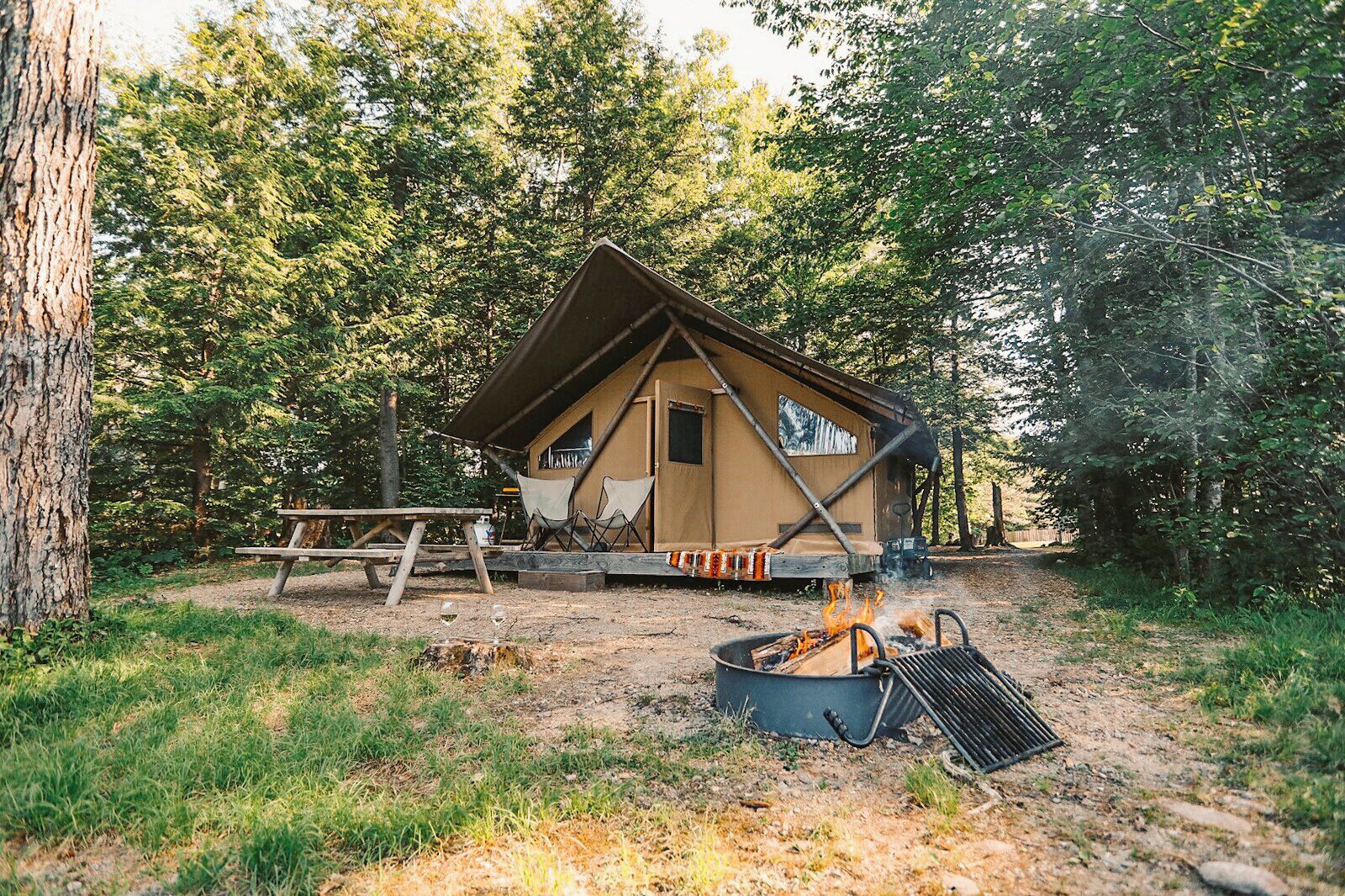 A rustic cabin with a fire pit and picnic table in a wooded area.