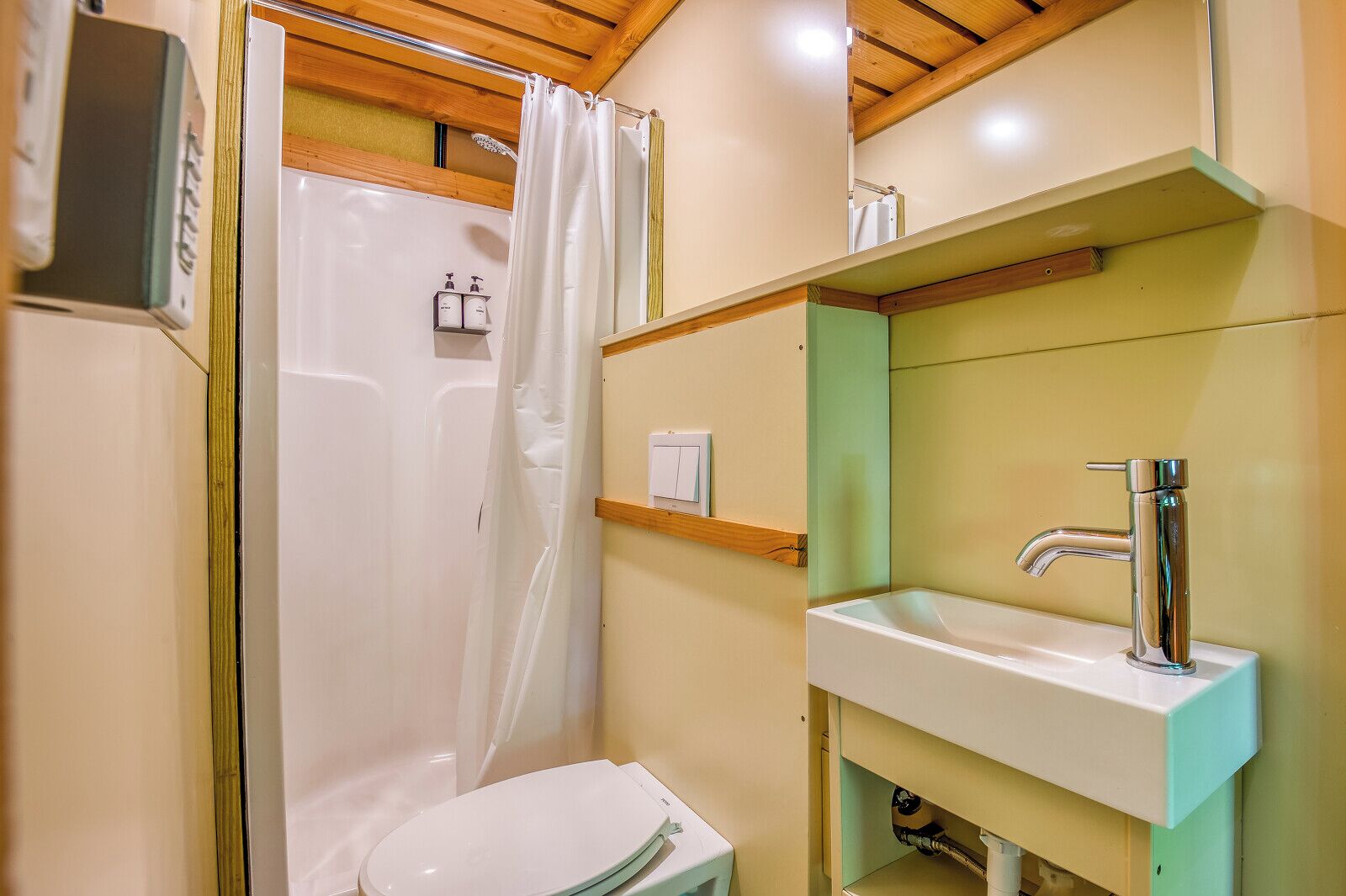 A bathroom with a shower, toilet, sink, and mirror.
