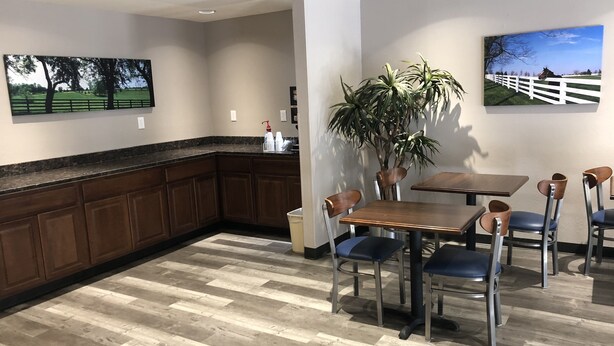 A dining area with a wooden table and chairs, a potted plant, and artwork on the walls. - DuPont Suites (Louisville)