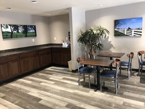 A dining area with a wooden table and chairs, a potted plant, and artwork on the walls. - DuPont Suites (Louisville)