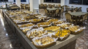 A buffet with various food items in baskets, surrounded by tables and chairs in a spacious dining area. - Lacqua DiRoma Hotel e Parque- ABD turismo (Caldas Novas)