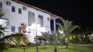 A white building with blue trim and multiple windows, surrounded by a well-maintained garden with palm trees and flowers. - Lacqua DiRoma Hotel e Parque- ABD turismo (Caldas Novas)