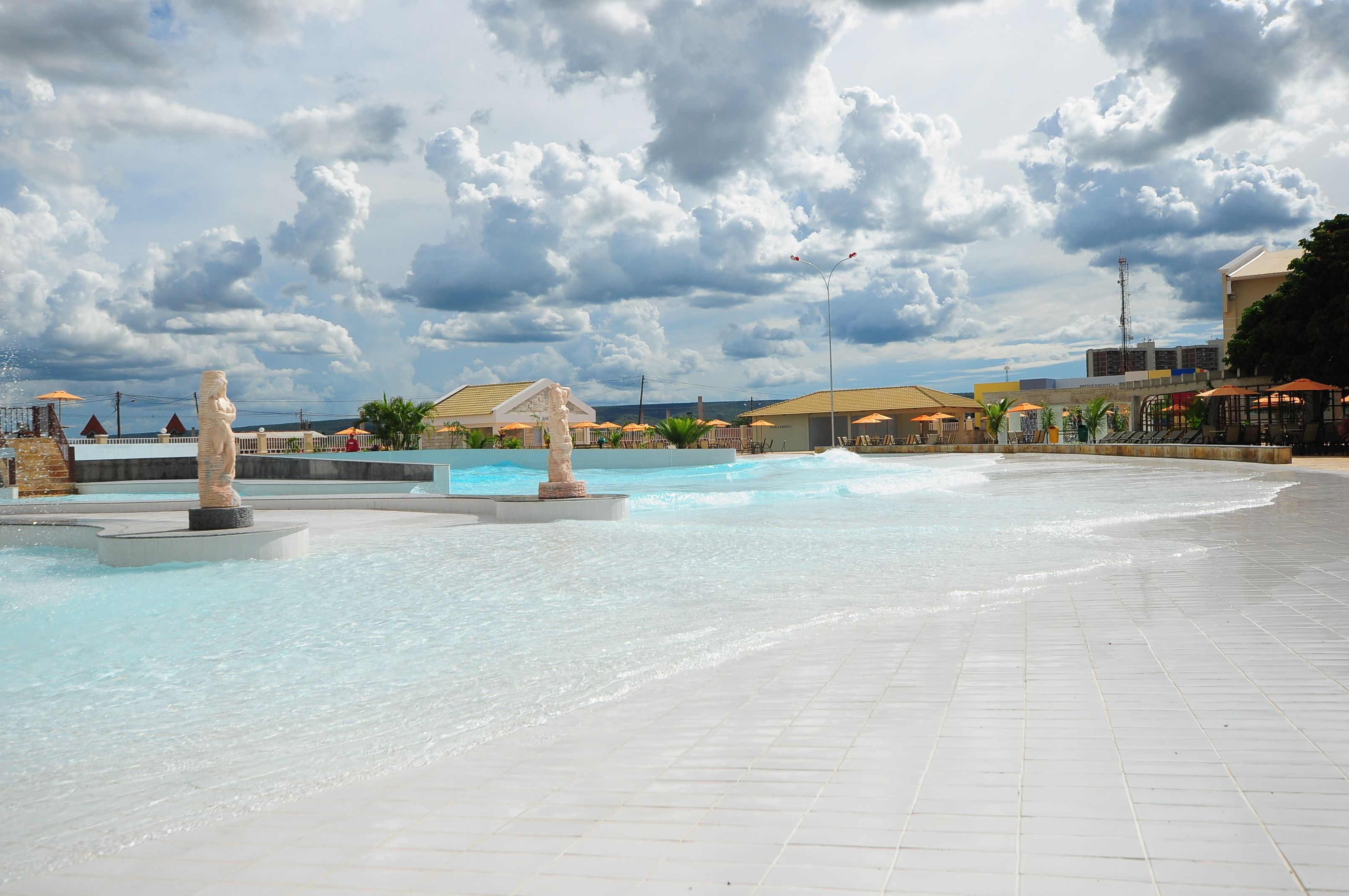 A public square with a water feature, including a fountain and a pool, under a cloudy sky.