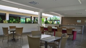 A spacious indoor dining area with wicker chairs and tables, a counter, and a view of greenery outside. - ABD Turismo Hoteis e Parques- Lacqua DiRoma (Caldas Novas)