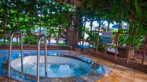 A hot tub with metal railings and a tiled floor, surrounded by greenery and a sign in a foreign language. - ABD Turismo Hoteis e Parques- Lacqua DiRoma (Caldas Novas)