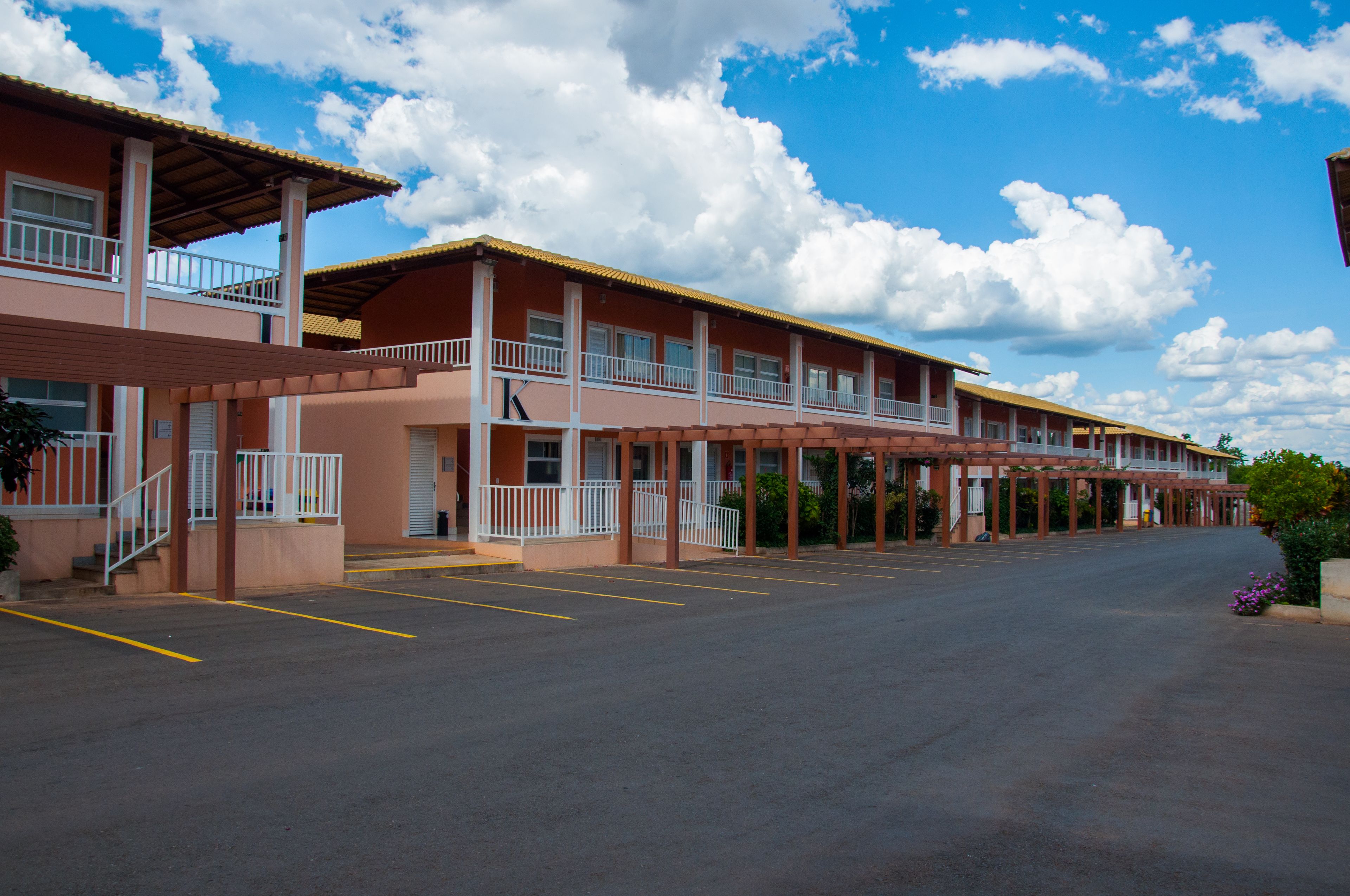 Um motel com área de estacionamento coberta e uma fileira de quartos com varandas.