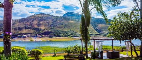 A serene lakeside setting with a gazebo, a bench, and lush greenery.