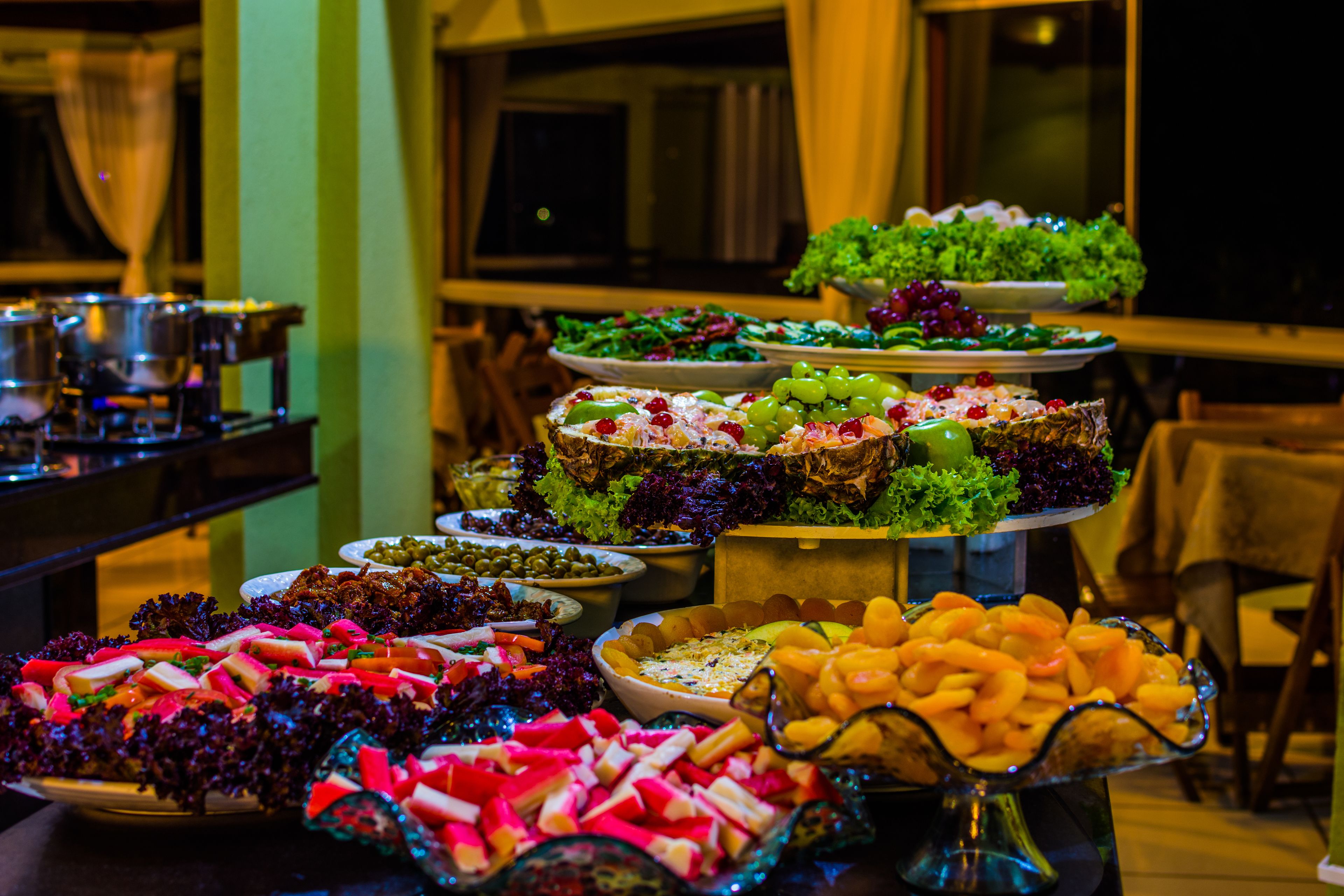 A buffet with various dishes including salads, fruits, and appetizers.