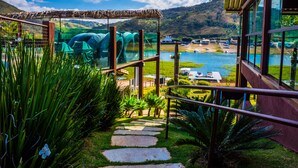 Un sendero conduce a una zona con paredes de vidrio que ofrece vistas a un lago y montañas.